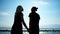 Young couple walking on coast holding each other hand, romantic couple in sunbeam, love in air
