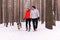 Young couple walking a dog in the winter forest, the dog wants to play