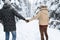 Young Couple Walking In Snow Forest Outdoor Man And Woman Holding Hands Back View