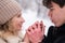 A young couple walks in the winter in the forest. The guy warms the girl's hands.