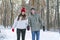 Young couple walks in winter through the forest and holds hands. Happy smiling lovers walk in snowy park