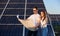 Young couple watching a plan on background of solar panels.