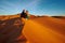 Young couple watching the sunrise on the sand dune in Sahara desert