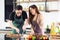 A young couple wearing apron very happy after helping to make a steak at the kitchen in their home, smile, and looking the steak