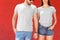 Young couple wearing gray t-shirts near color wall