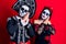 Young couple wearing mexican day of the dead costume over red sleeping tired dreaming and posing with hands together while smiling