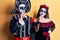 Young couple wearing mexican day of the dead costume over yellow with hand on chin thinking about question, pensive expression