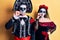 Young couple wearing mexican day of the dead costume over yellow mouth and lips shut as zip with fingers