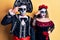 Young couple wearing mexican day of the dead costume over yellow pointing unhappy to pimple on forehead, ugly infection of