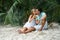 The young couple, the woman and the man sit on the beach and will take the selfies dressed in bright clothes and in sunglasses.