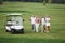 Young couples getting ready to play. A group of smiling friends came to the hole on a golf cart