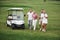 Young couples getting ready to play. A group of smiling friends came to the hole on a golf cart