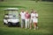 Young couples getting ready to play. A group of smiling friends came to the hole on a golf cart