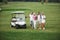 Young couples getting ready to play. A group of smiling friends came to the hole on a golf cart