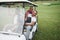 Young couples getting ready to play. A group of smiling friends came to the hole on a golf cart