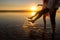 Young couples is walking in the water on summer beach. Sunset over the sea.Two silhouettes against the sun. Feet doing splashes of
