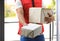 Young courier holding parcels on doorstep. Delivery service