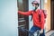 Young courier man with thermal backpack and bike ringing the doorbell - Focus on face