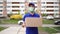 A young courier in a medical mask on his face carries a cardboard box