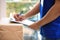 Young courier with parcels and clipboard against background, closeup. Delivery service