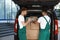 Young couriers near delivery car with many parcels