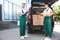 Young couriers with parcels near delivery car