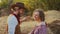 Young cowboy puts on his hat on woman`s head on farm with sun light on background