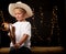Young cowboy sitting on hay bale with his stick horse