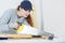 Young craftswoman cutting wooden board with handsaw indoors