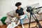 Young creative afro american woman, female art blogger sitting on sofa at home and drawing, recording new video tutorial