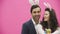 Young creative couple on pink background. With hackneyed ears on the head. During this, the wife holds decorative