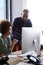 Young creative professionals working together at a computer in an office, vertical, close up