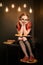 Young creative student with glasses and red pigtails with book with illuminated Edison lamps in the background