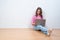 Young creative woman sitting in the floor with laptop./ Casual b