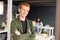 Young cross-armed businessman in casualwear standing by open door of office