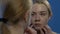 Young crying girl looking at face acne in mirror, suffering from skin problems