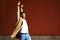 Young Cuban man dancing on red urban wall.