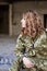 Young curly blond military woman, wearing ukrainian military uniform, sitting on pavement edge. Close-up portrait of army female