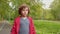 Young curly boy walking on road in summer park. Portrait teenager boy walking in green park. Face boy looking to camera