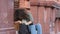 Young curly-haired African American girl sitting on steps outdoors nervously looking in her bag for keys, wallet or