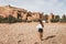 Young curly woman walking on background of Ait-Ben-Haddou. Travel in Morocco