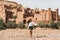 Young curly woman walking on background of Ait-Ben-Haddou. Travel in Morocco