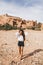 Young curly woman walking on background of Ait-Ben-Haddou. Travel in Morocco