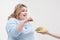 Young curvy fat woman in casual blue clothes on a white background sneaking off a plate of hamburger and french fries
