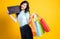 Young and cute Asian woman posing in shopping concept holding several shopping bags and signboard.