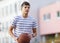 Young cute boy plays basketball at the outdoor streetball court on a sunny summer day. Teenager player in action dribbling