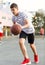 A young cute boy plays basketball at the outdoor streetball court on a sunny summer day. Teenager player in action dribbling