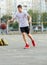 A young cute boy plays basketball at the outdoor streetball court on a sunny summer day. Teenager player in action dribbling