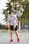 A young cute boy plays basketball at the outdoor streetball court on a sunny summer day. Teenager player in action dribbling