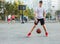 A young cute boy plays basketball at the outdoor streetball court on a sunny summer day. Teenager player in action dribbling